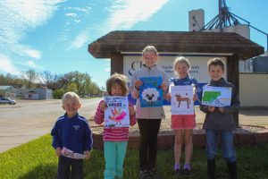 Five children holding up drawings in front of a CHS location