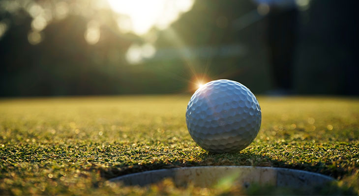Golf ball by a hole on the green